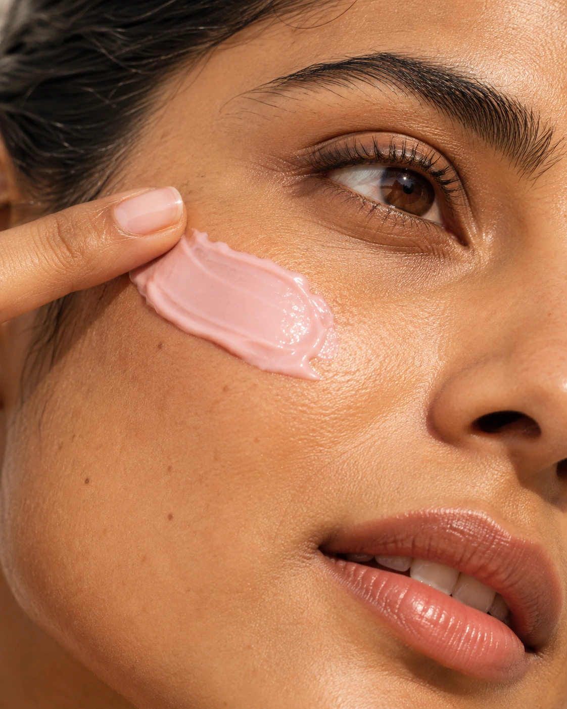 A new Naish model gently applying blush-pink cream to her cheek